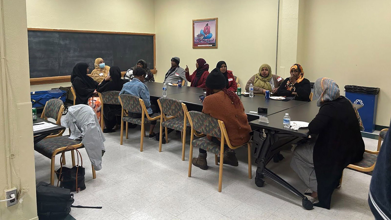 A group of people sitting around a conference table with a blackboard behind them.