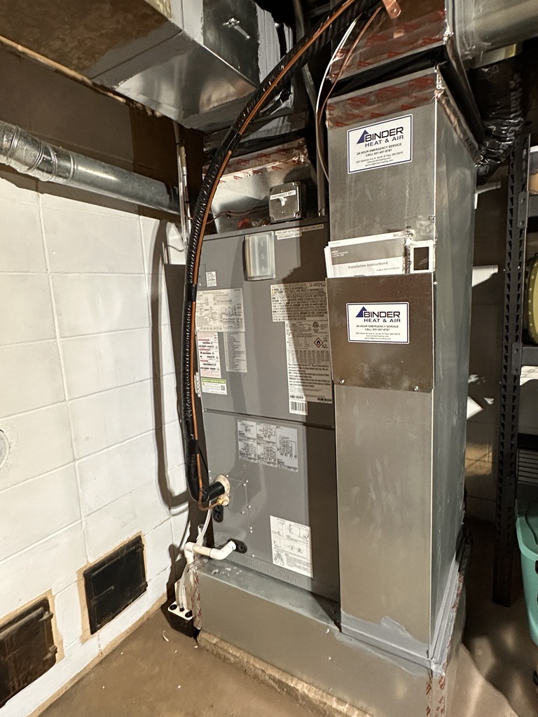 A large, gray heat pump in Sam's basement.
