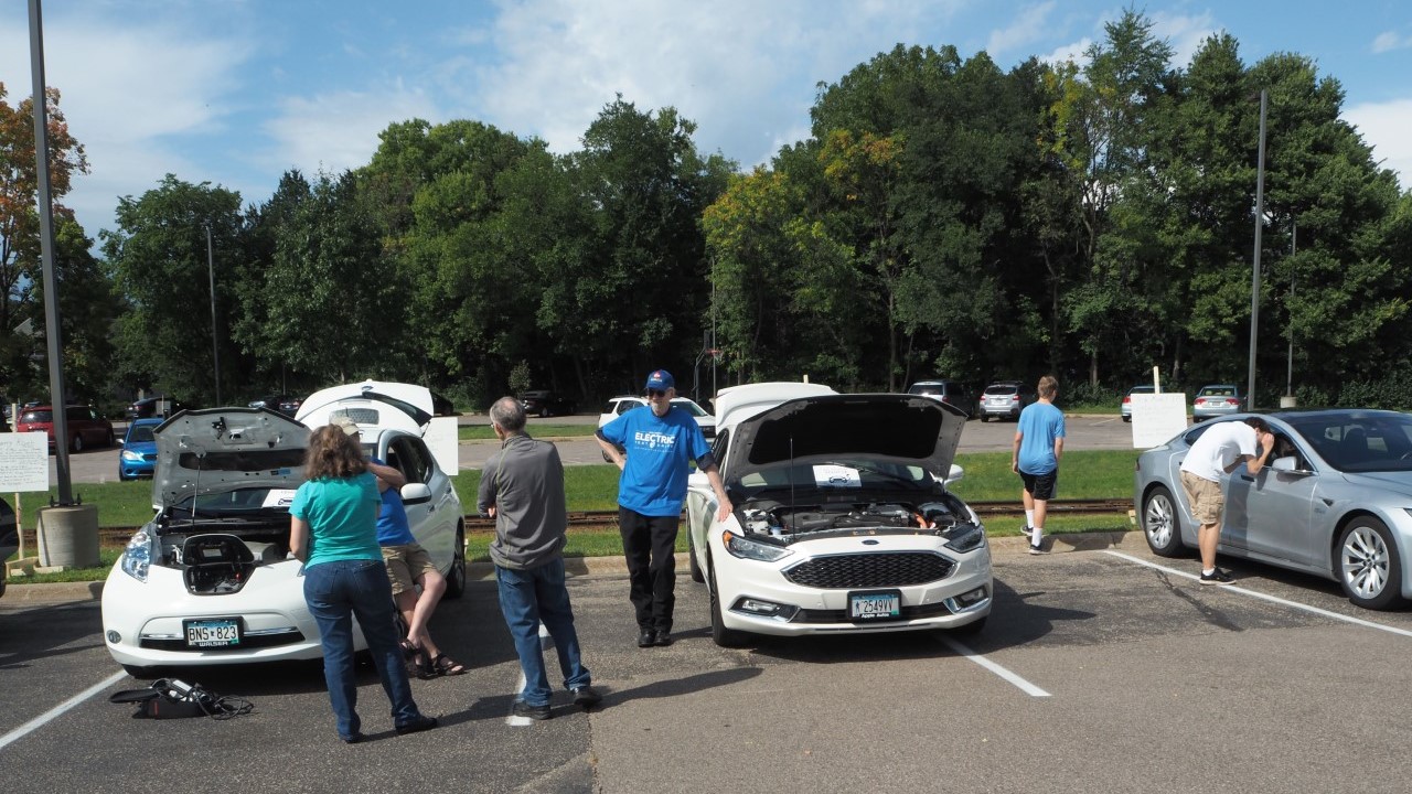 people gathered around several electric vehicles
