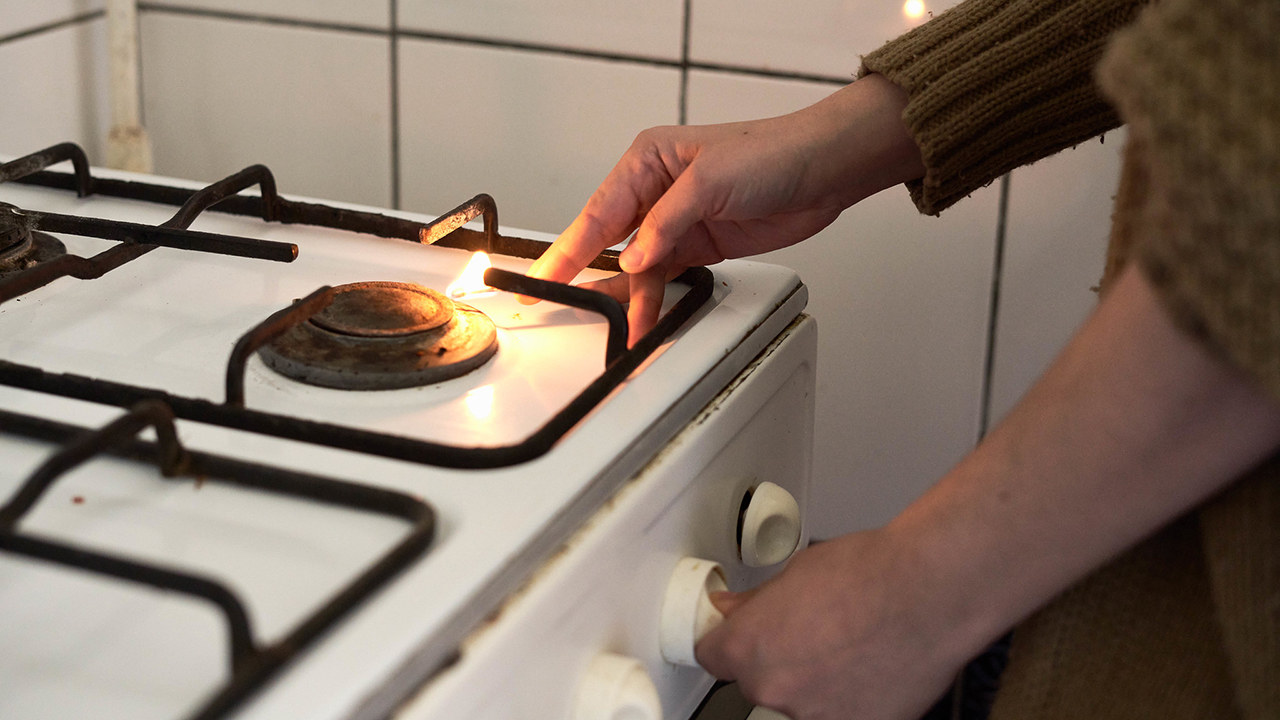 woman lighting gas stove with match