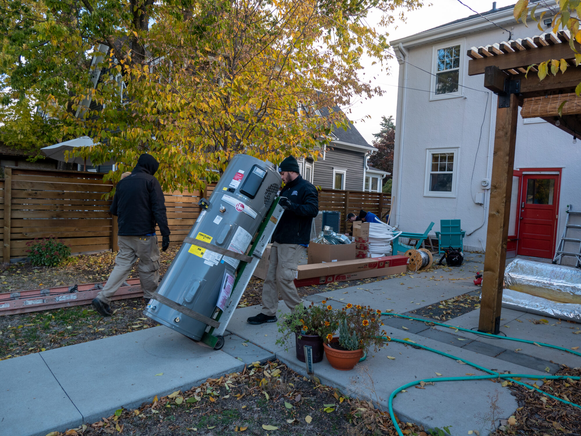 Two workers moving a brand new heat pump water heater in to a house.