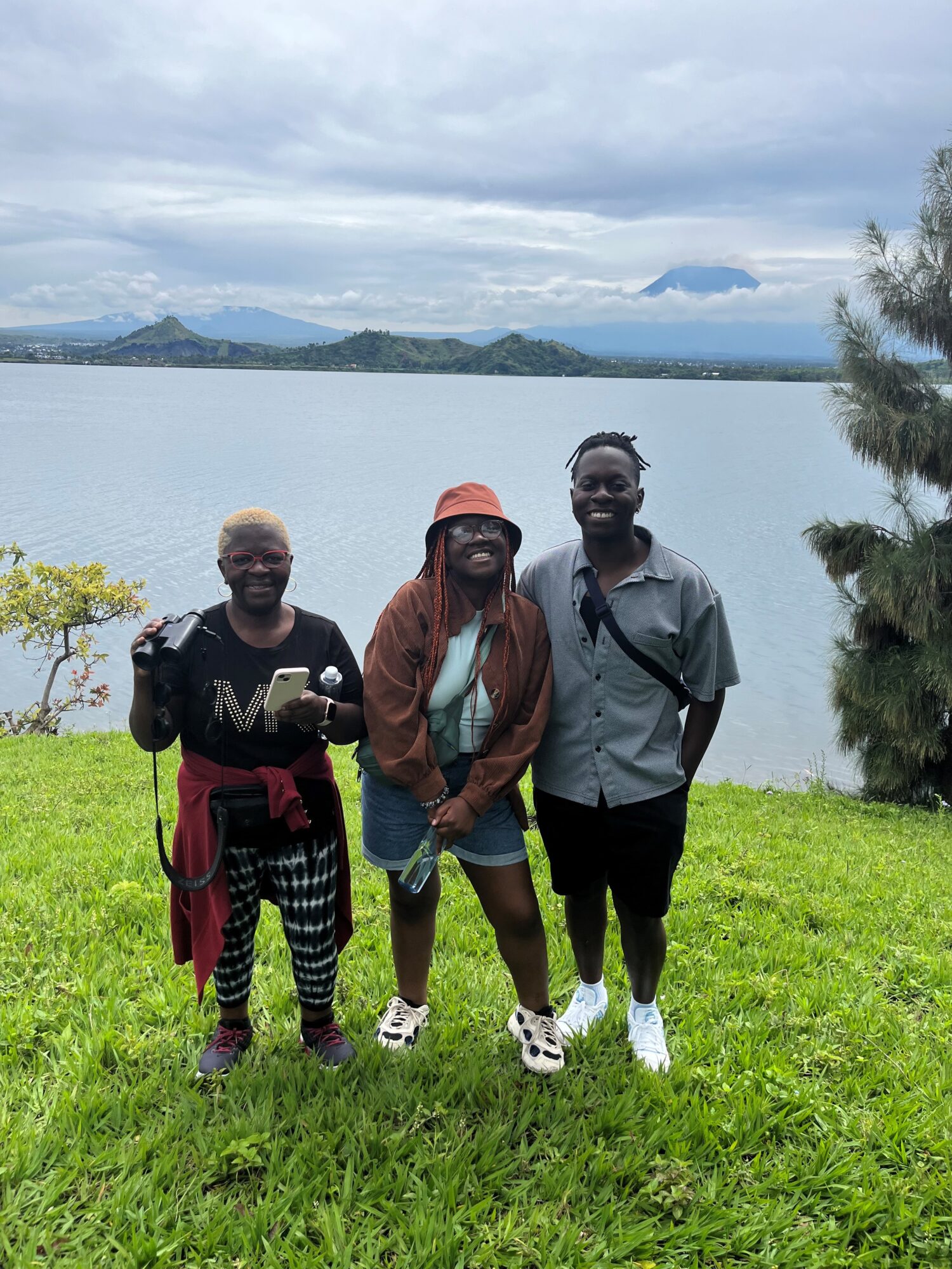 Three people smiling in front of scenic lake in the Congo