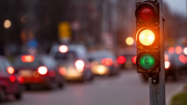 city crossing with a semaphore on blurred background with cars in the evening streets, orange light
