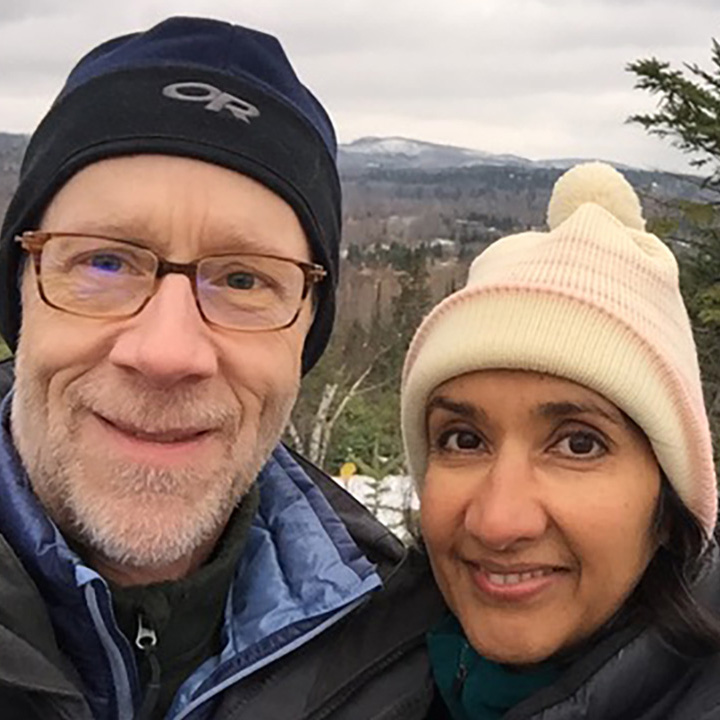 Eric and Geeta smiling with beautiful snowy mountain scenery behind them.